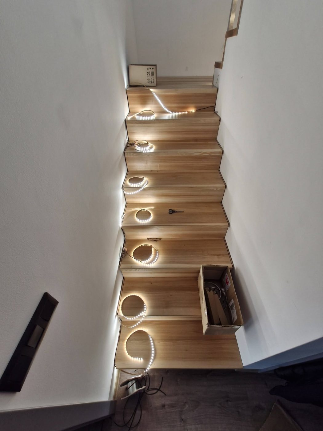 LED pásky rozložené na schodech před montáží